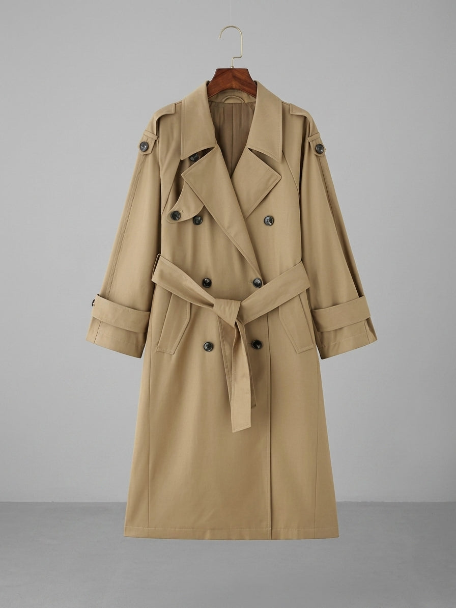 A classic double-breasted trench coat in beige, hanging on a wooden hanger against a neutral gray studio background.
