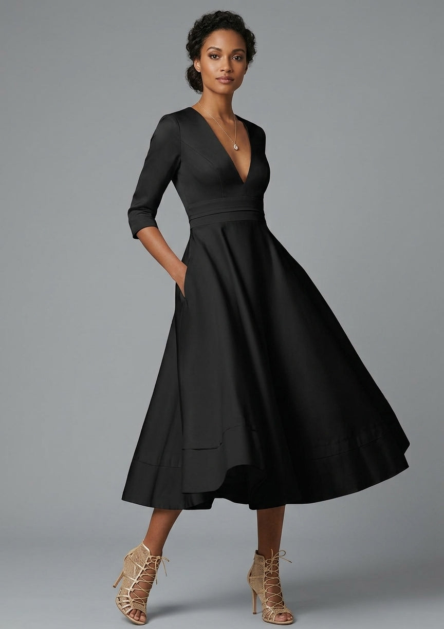 A woman modeling a black midi dress with three-quarter sleeves, a deep V-neckline, and a flared skirt, paired with beige lace-up heeled sandals against a solid gray studio background.