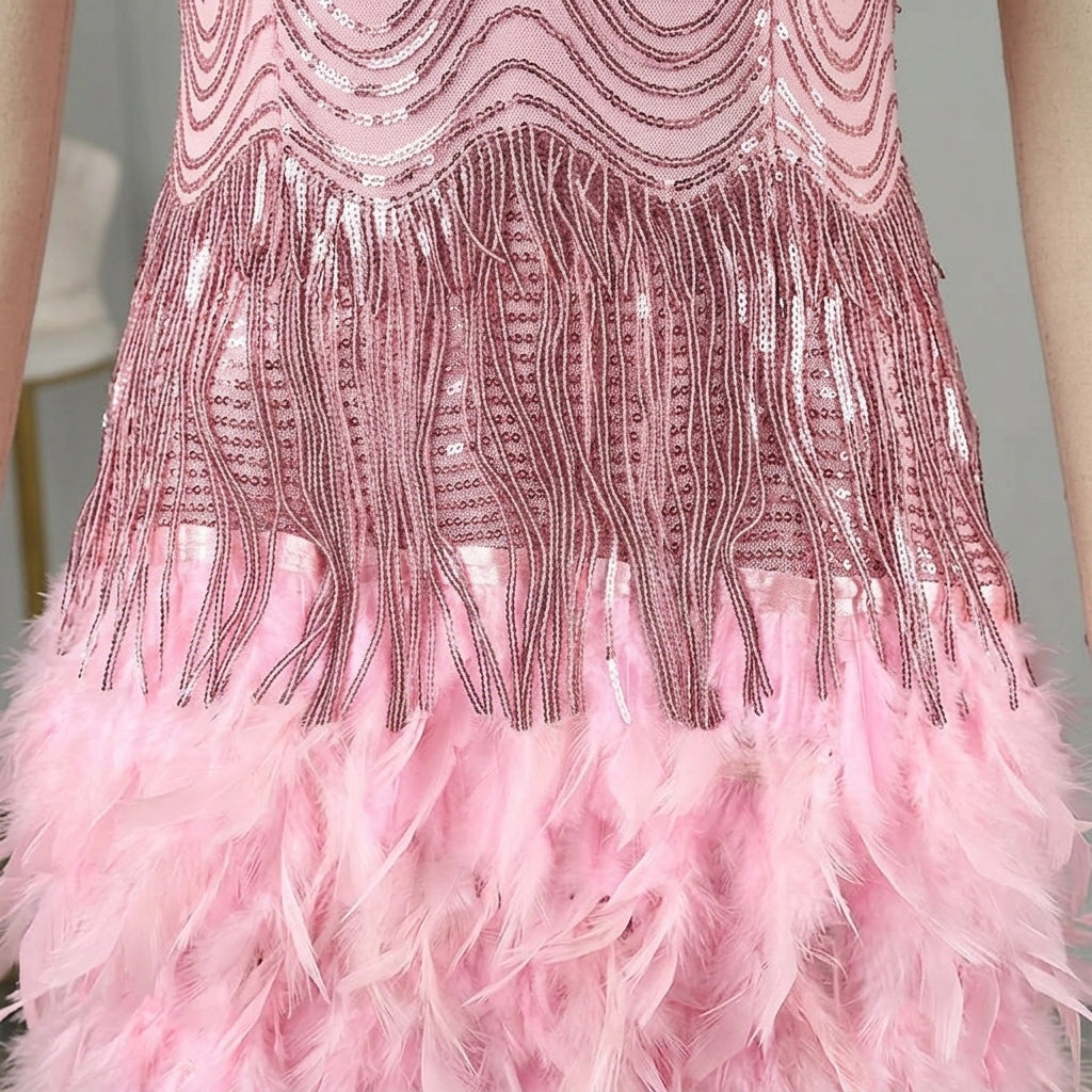 Close-up of a pink flapper-style dress with sequined fringe and a fluffy feathered hem, shown on a model.