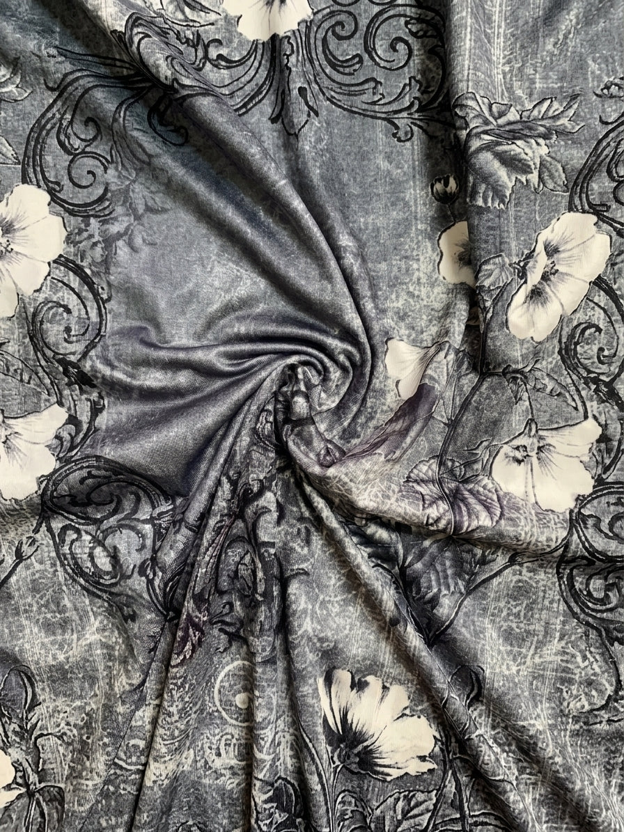 A close-up of draped fabric with a gray and black ornate floral pattern, showing the material's texture and sheen.