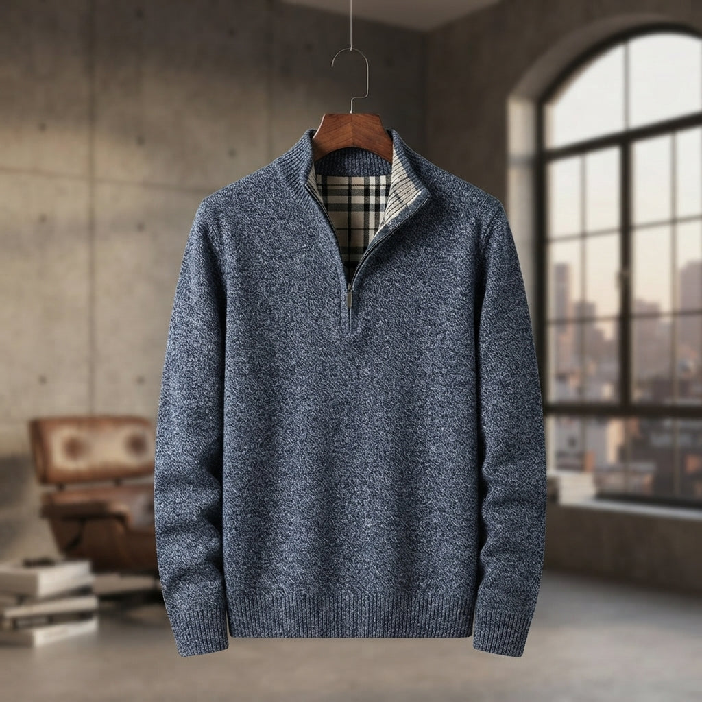 A men's blue-gray quarter-zip knit sweater with a plaid lining visible at the collar, hanging on a wooden hanger against a blurred loft-style background with a large window.