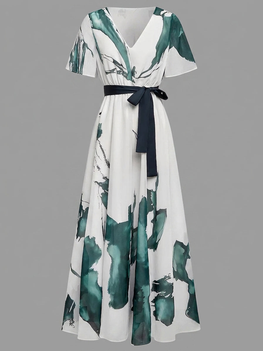 A white maxi dress with a dark green watercolor floral print, featuring short flutter sleeves, a V-neckline, and a matching dark green tie belt at the waist.