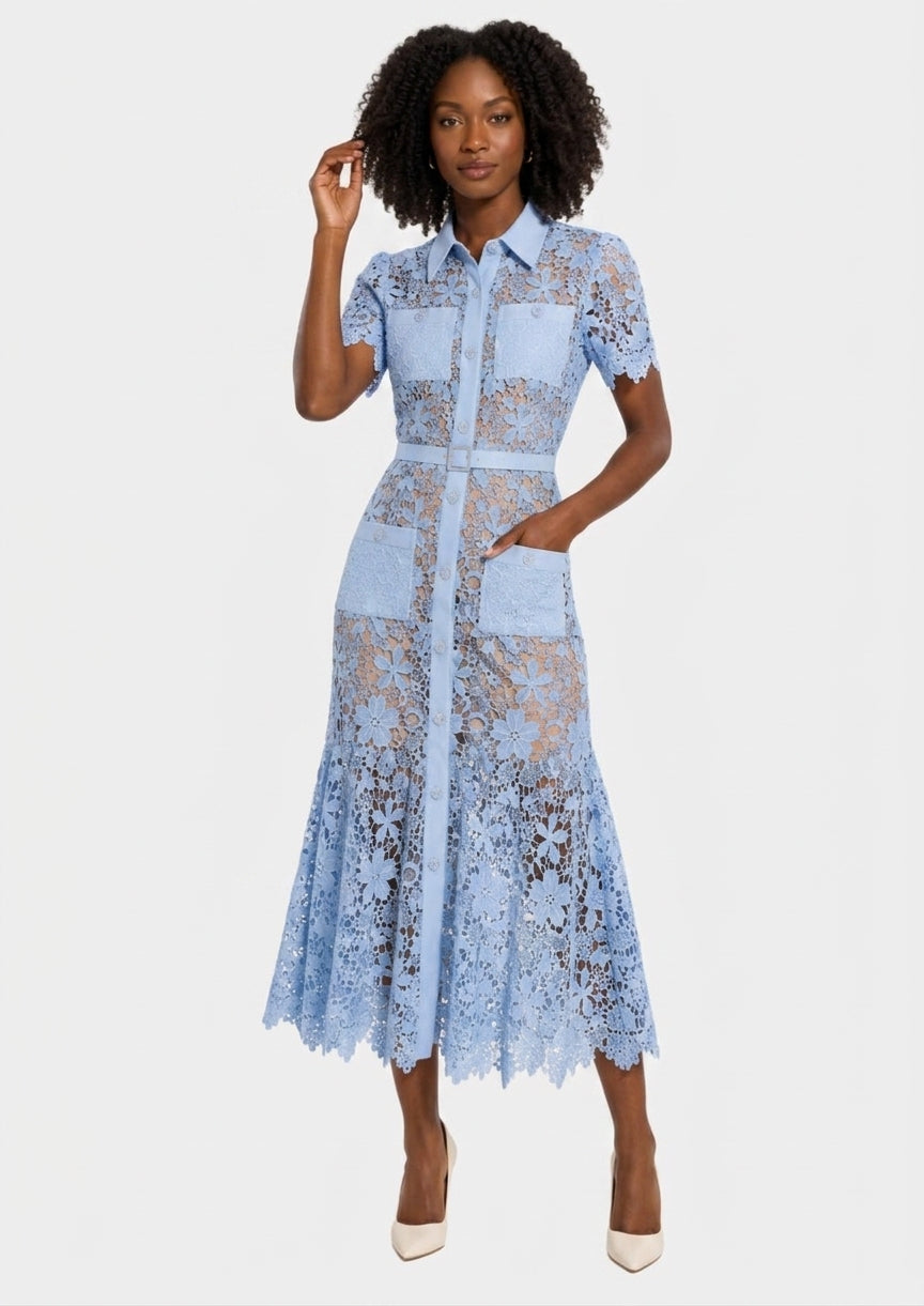 A woman modeling a light blue lace midi dress with short sleeves, a button-up front, and a flared skirt, photographed against a plain light gray studio background.