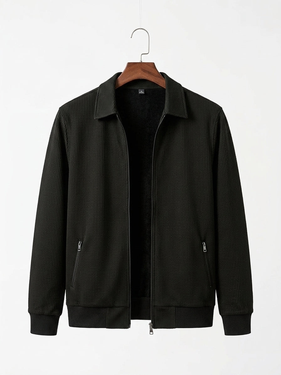A black textured zip-up jacket with a collar, hanging on a wooden hanger against a plain white background.
