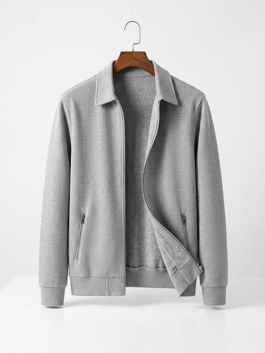 A light gray waffle-knit zip-up jacket with a pointed collar, displayed on a wooden hanger against a clean white background.