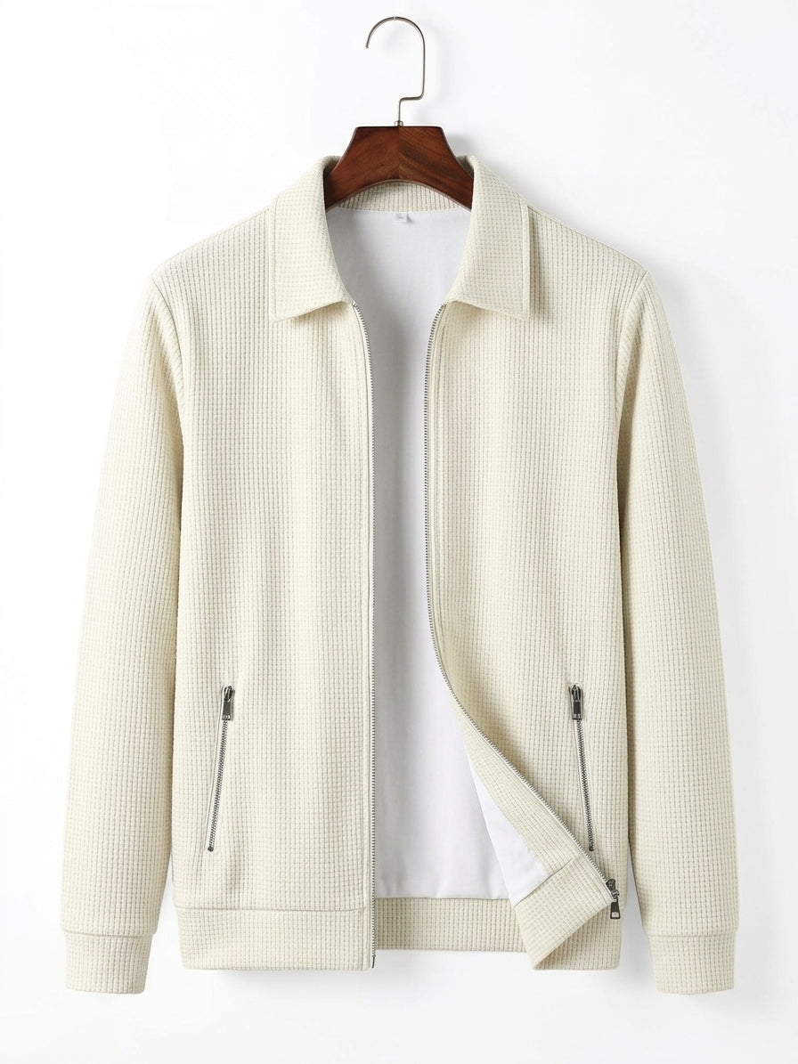 An off-white waffle-knit zip-up jacket with a collar, hanging on a wooden hanger against a plain white background.