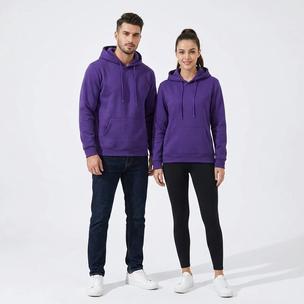 A man and a woman modeling matching purple pullover hoodies with drawstrings and front kangaroo pockets, paired with dark jeans and black leggings respectively, against a clean white studio background.