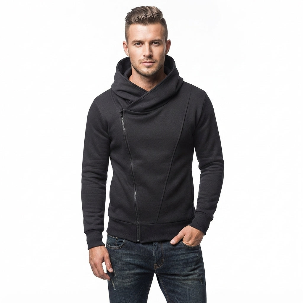 A man wearing a black asymmetrical zip-up hoodie with a cowl neck and dark blue jeans, standing against a plain white background.