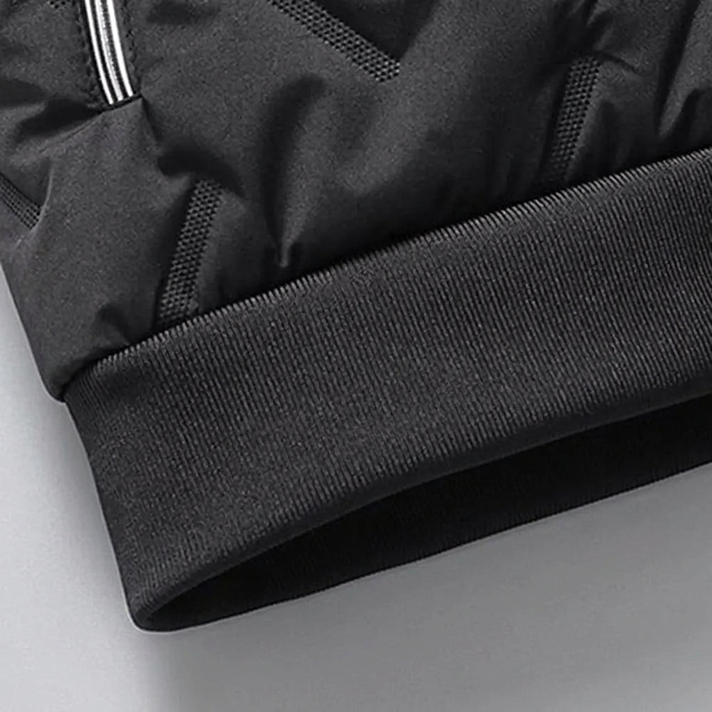 Close-up detail of a black puffer jacket showing the ribbed knit cuff and a portion of the quilted fabric with a silver zipper pull.