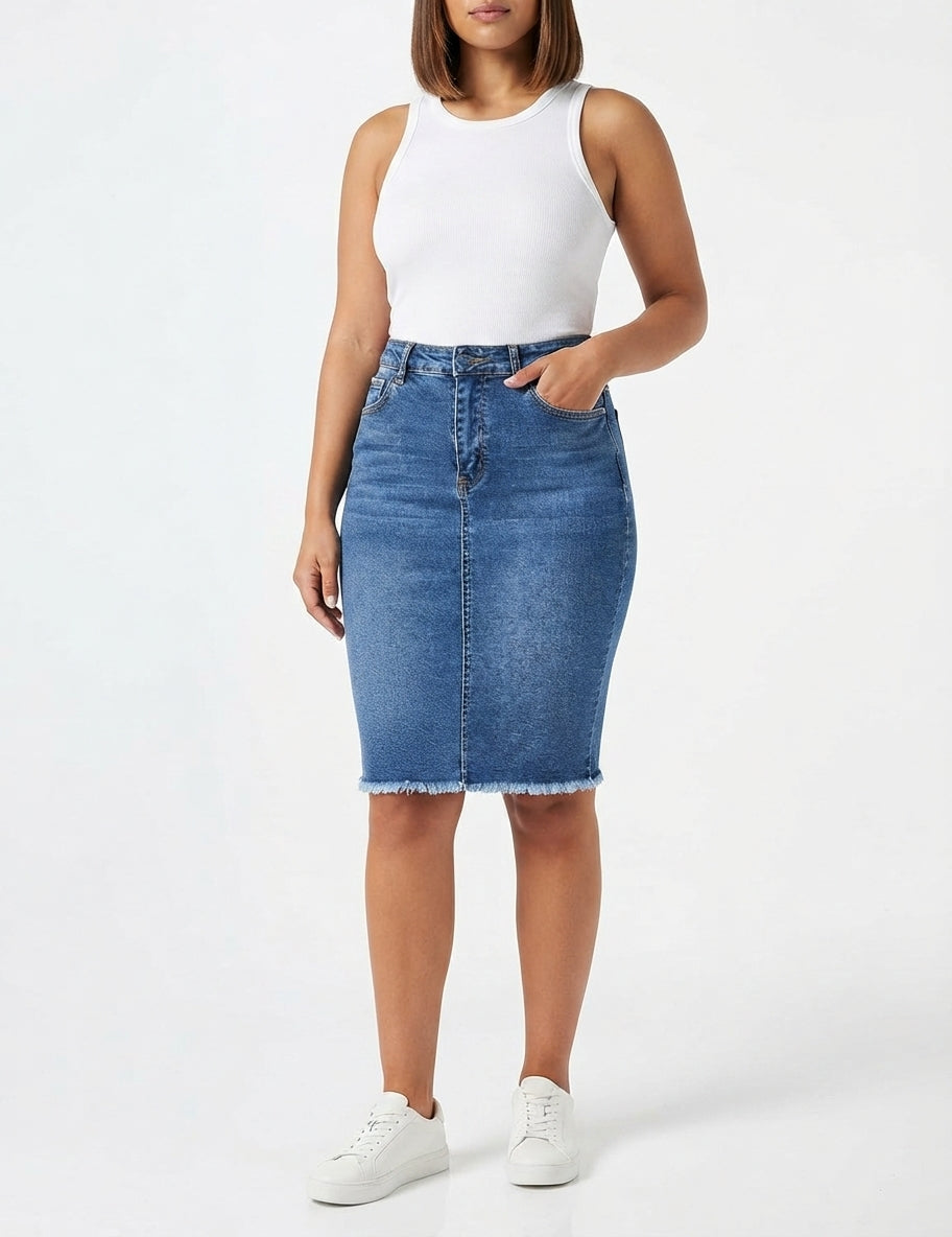 A model wearing a blue denim pencil skirt with a frayed hem, paired with a white sleeveless top and white sneakers, against a plain white studio background.