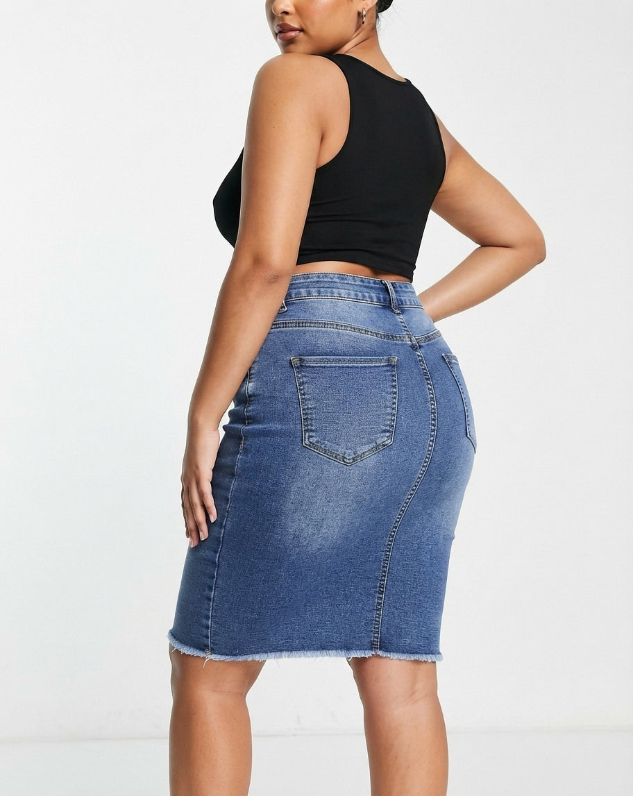 A woman wearing a blue denim pencil skirt with a frayed hem and a black sleeveless crop top, shown from a side-back angle against a plain white studio background.