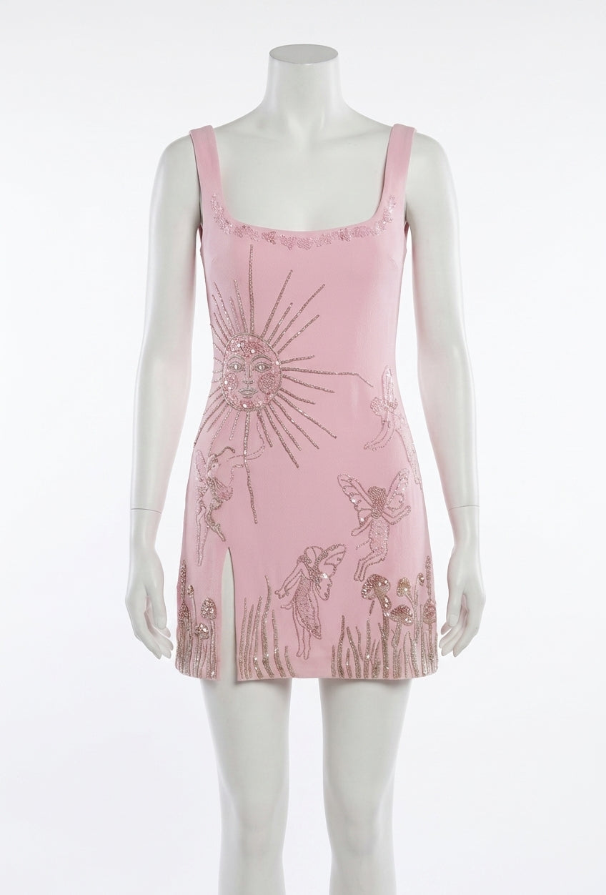A pink sleeveless mini dress with embroidered sun, fairies, and grass motifs, displayed on a white mannequin against a white background.