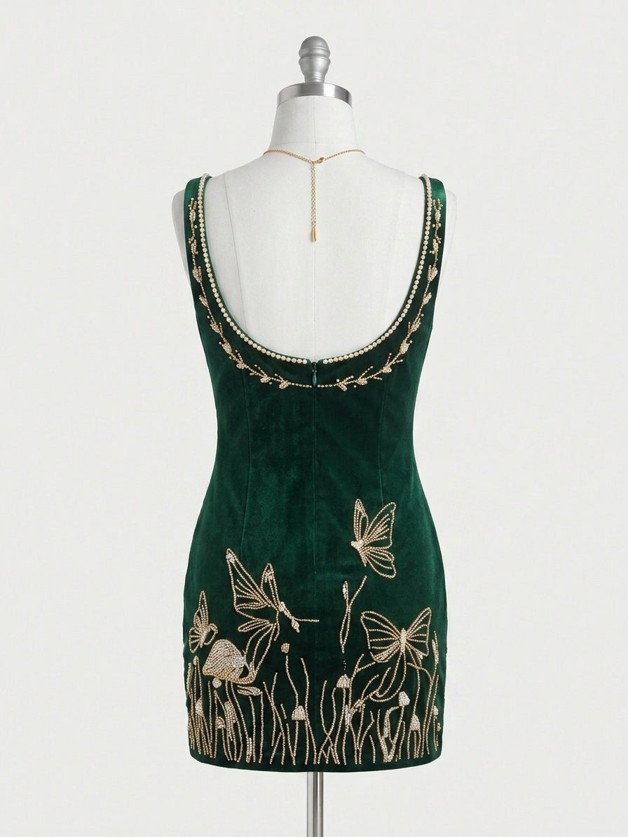 A dark green velvet sleeveless dress displayed on a white mannequin torso, featuring gold embroidered butterflies and grass motifs near the hem and a gold beaded neckline.