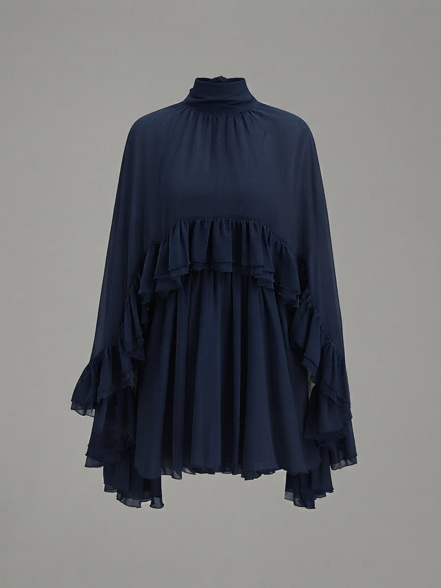 A navy blue high-neck blouse with layered ruffle details on the bodice and sleeves, displayed on a neutral gray background.