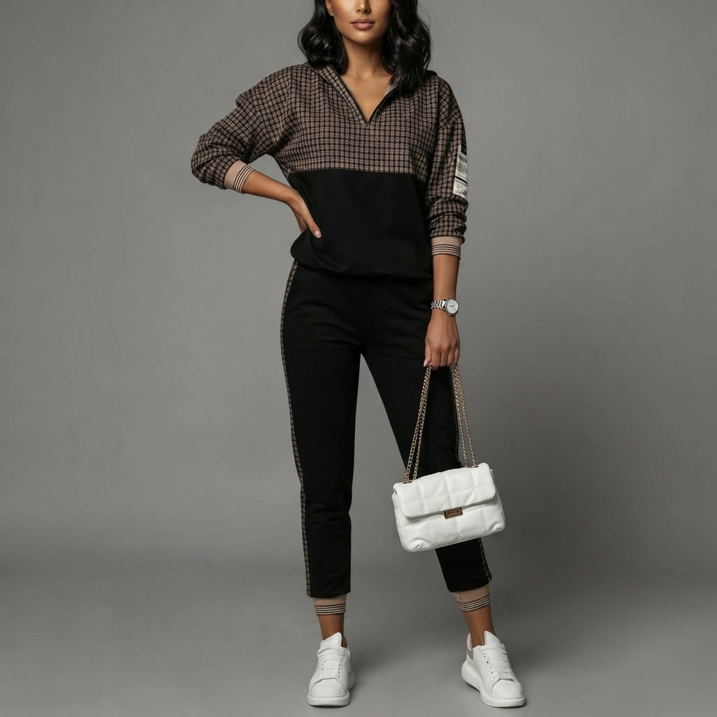 woman wearing a black track suit standing against a grey background