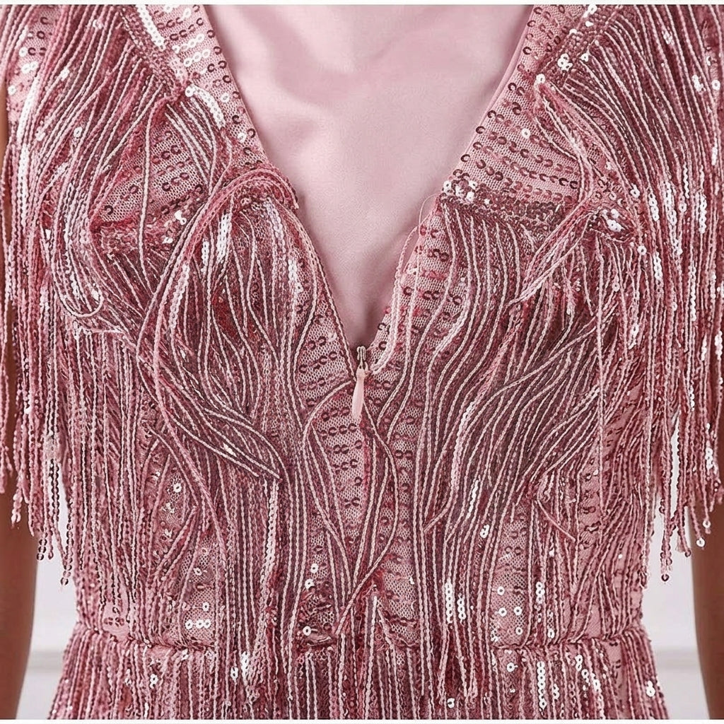 Close-up of a pink sequined fringed dress with a deep V-neckline and shimmering metallic details.