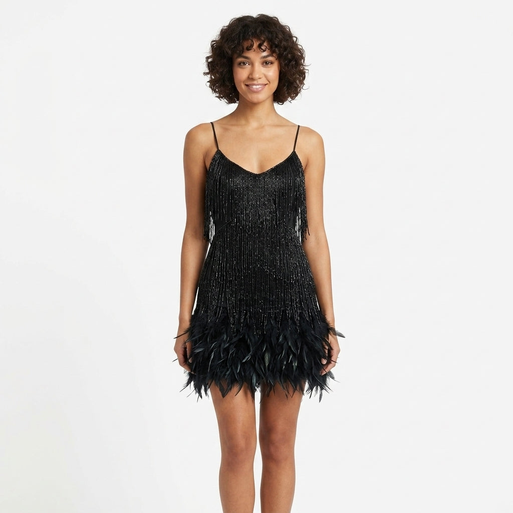 A woman modeling a black sequined mini dress with spaghetti straps and a feather-trimmed hem against a plain white studio background.