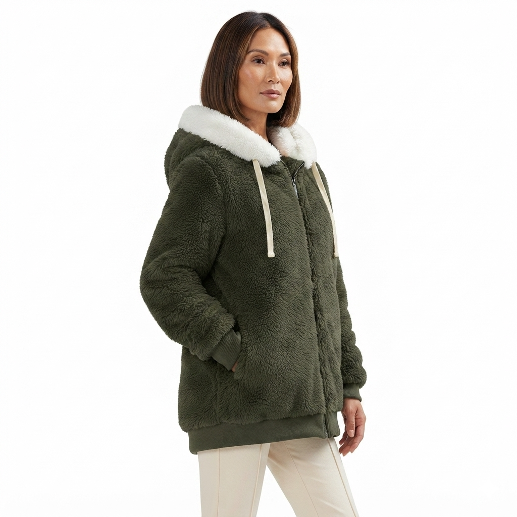 A woman wearing a dark olive green sherpa fleece hooded jacket with a contrasting white faux-fur collar and white drawstrings, paired with off-white pants, against a plain white background.