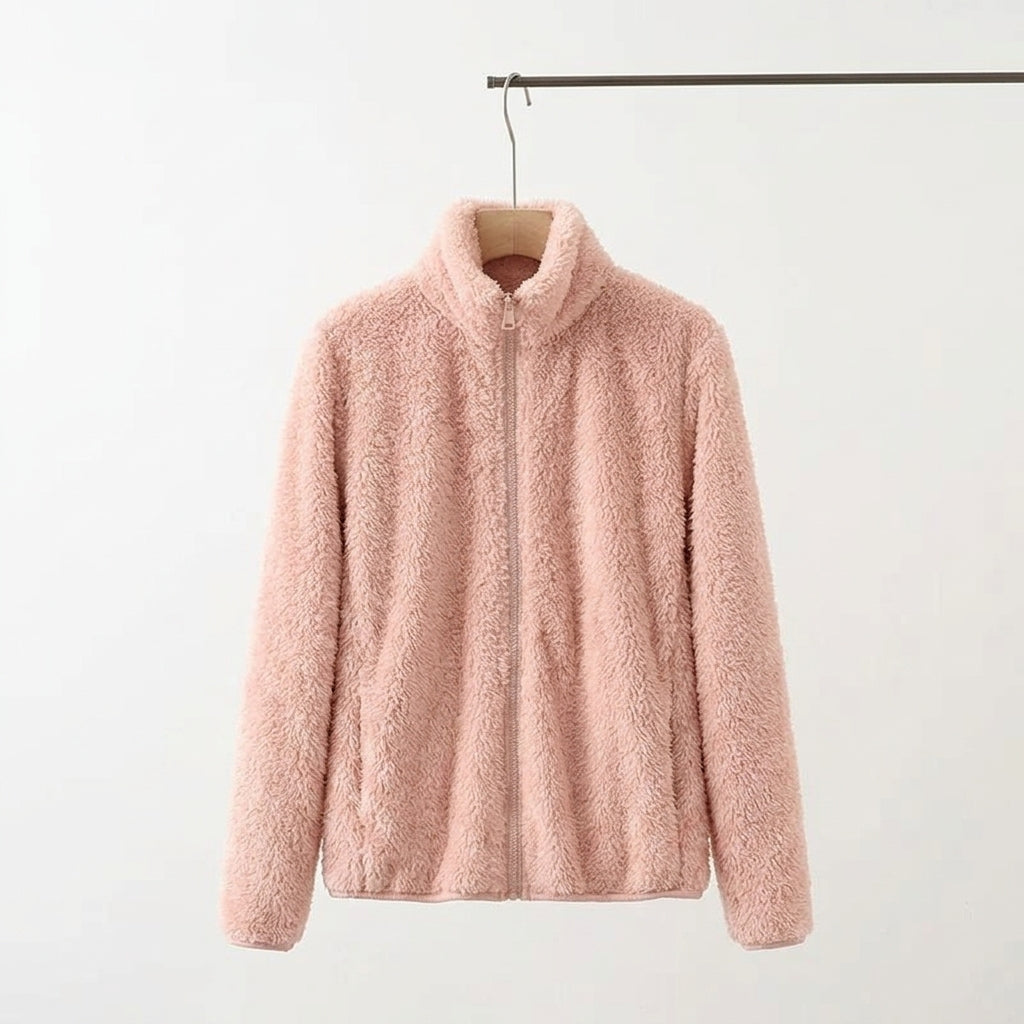 A light pink fuzzy fleece zip-up jacket with a mock neck collar, hanging on a wooden hanger from a metal clothing rack against a plain white background.