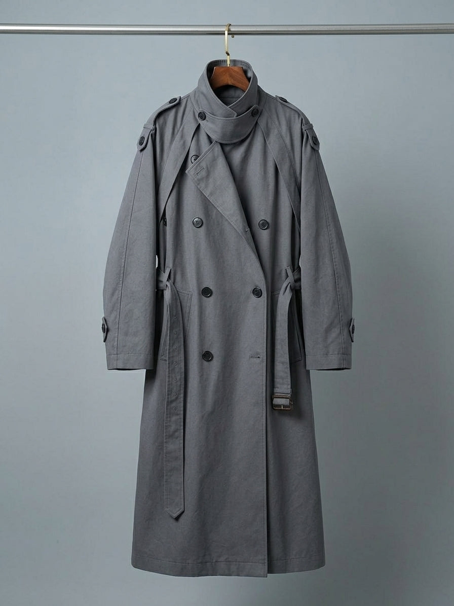 A gray double-breasted trench coat with a high collar and belt, hanging on a wooden hanger against a plain gray background.