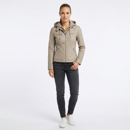 A woman modeling a light beige hooded jacket with dark gray slim-fit jeans and white sneakers, standing against a plain white studio background.