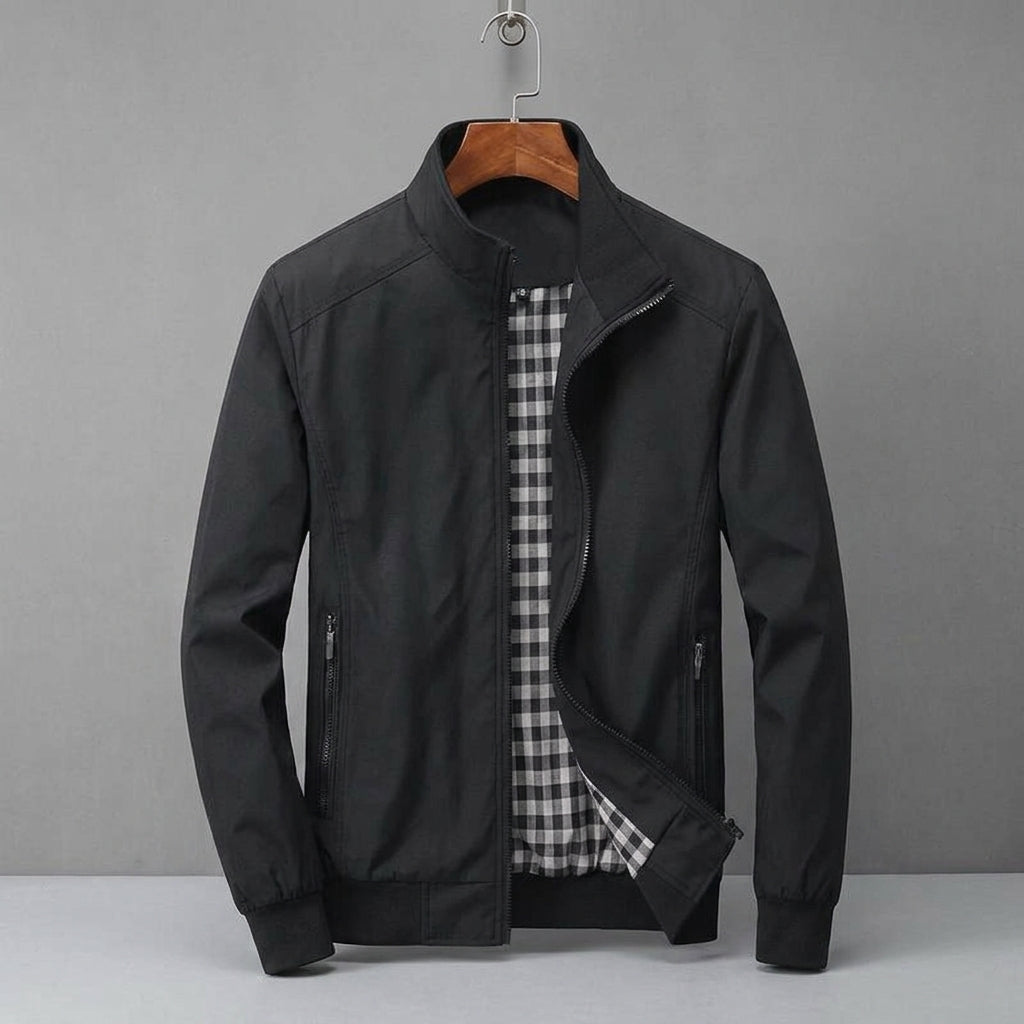 A black men's zip-up jacket with a stand collar, displayed on a wooden hanger against a neutral gray background. The jacket is open to show a black and white checkered lining.