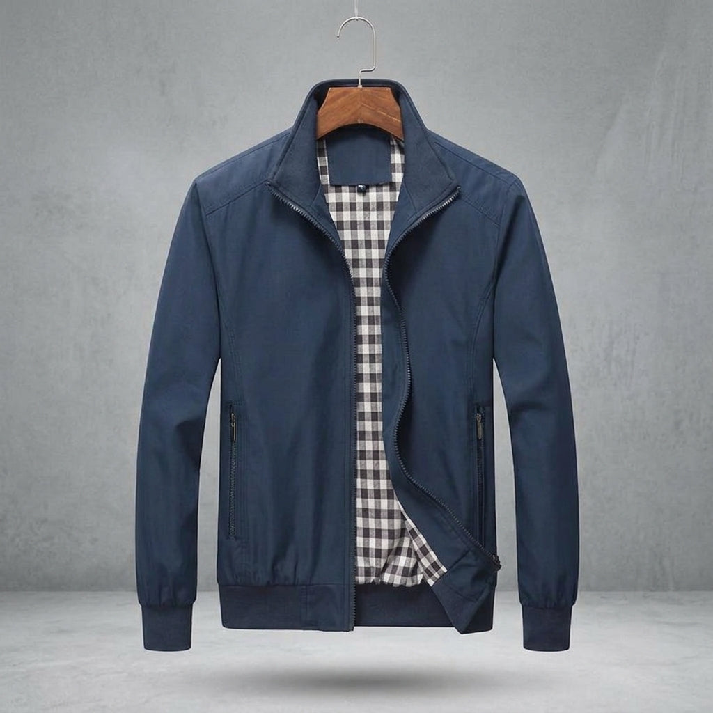 A navy blue men's zip-up jacket with a stand collar, displayed on a wooden hanger against a textured gray background. The jacket is open to show a black and white gingham patterned shirt lining inside.
