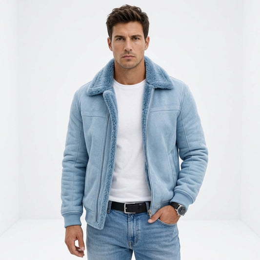 A man wearing a light blue suede shearling jacket with a plush collar, layered over a white t-shirt and blue jeans, standing against a white studio background.