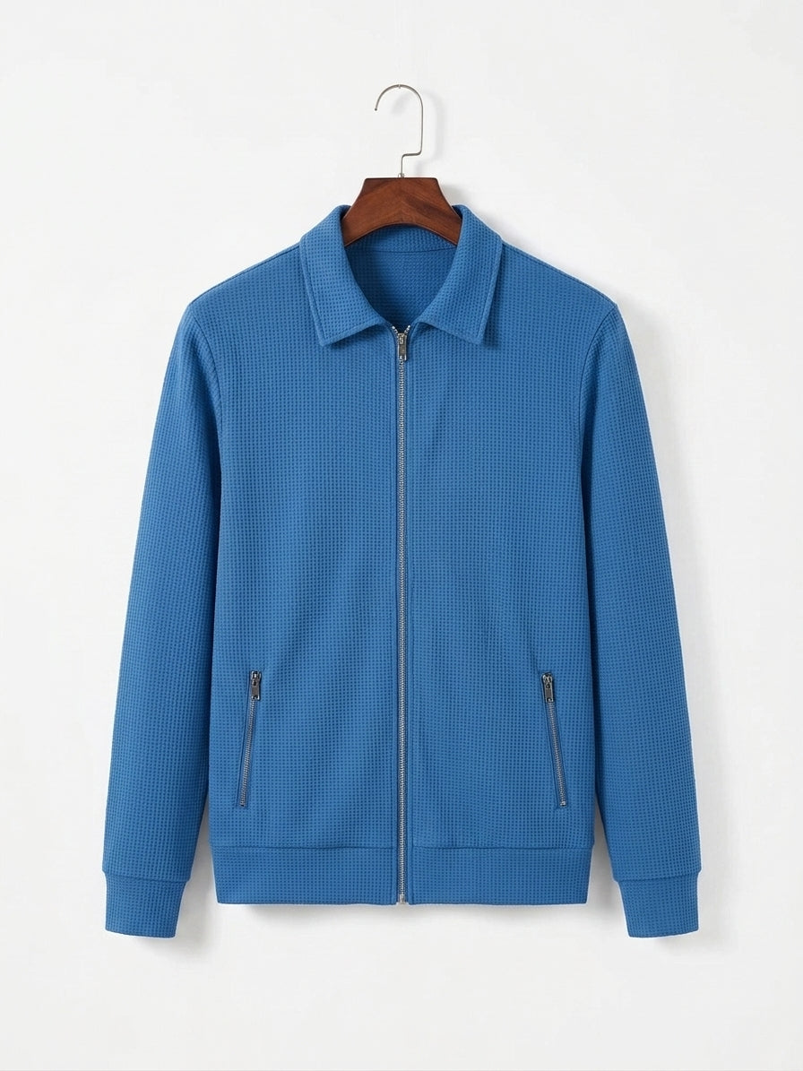A blue textured zip-up jacket with a collar and two zippered hand pockets, hanging on a wooden hanger against a plain white background.