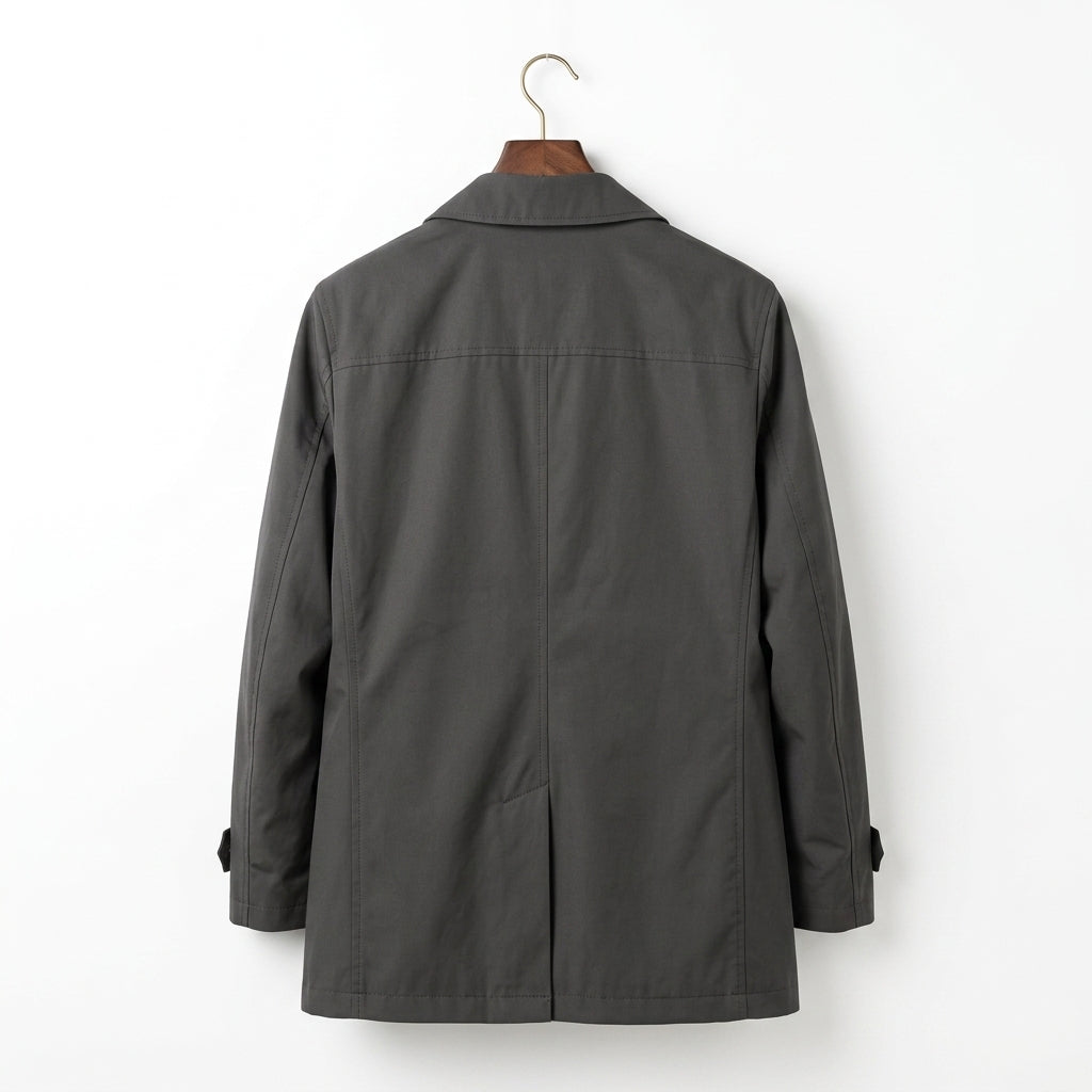 A dark gray utility jacket hanging on a wooden hanger against a plain white wall, showing the back view.