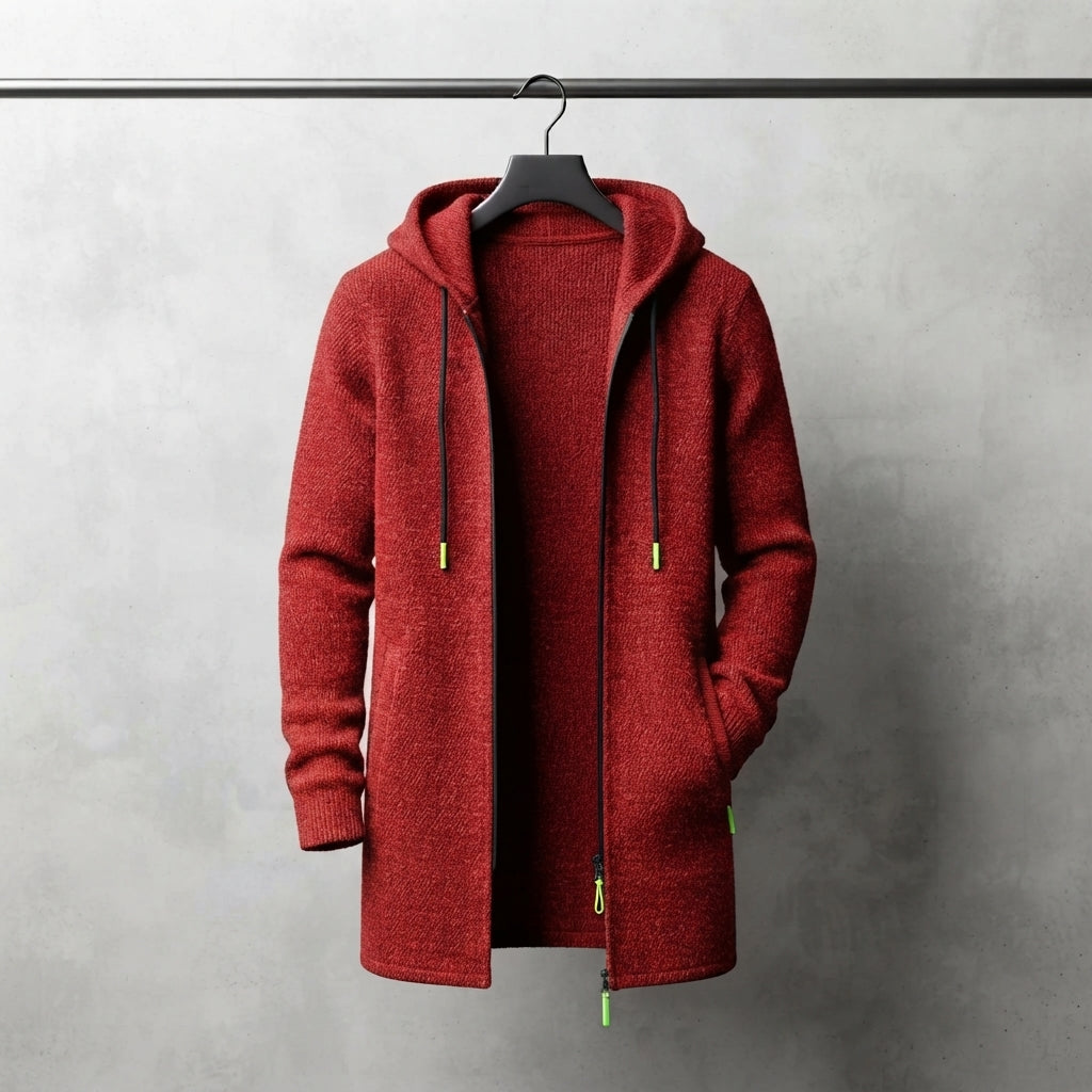 A red hooded zip-up jacket with black drawstrings and small lime green accents, hanging on a black hanger against a textured gray wall.