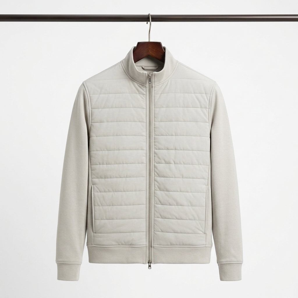 A light beige quilted zip-up jacket with a stand collar, hanging on a wooden hanger against a plain white background.