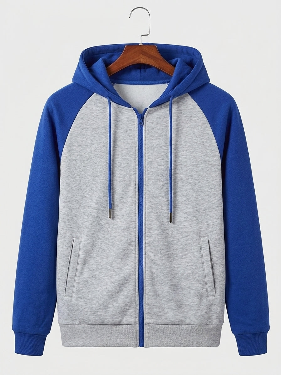 A colorblock zip-up hoodie with a heather gray body and royal blue raglan sleeves, hood, and zipper, hanging on a wooden hanger against a light gray background.
