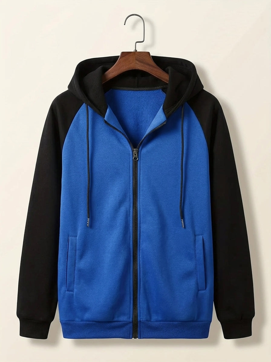 A colorblock zip-up hoodie with a bright blue body and black sleeves, hood, and zipper, hanging on a wooden hanger against a light beige background.