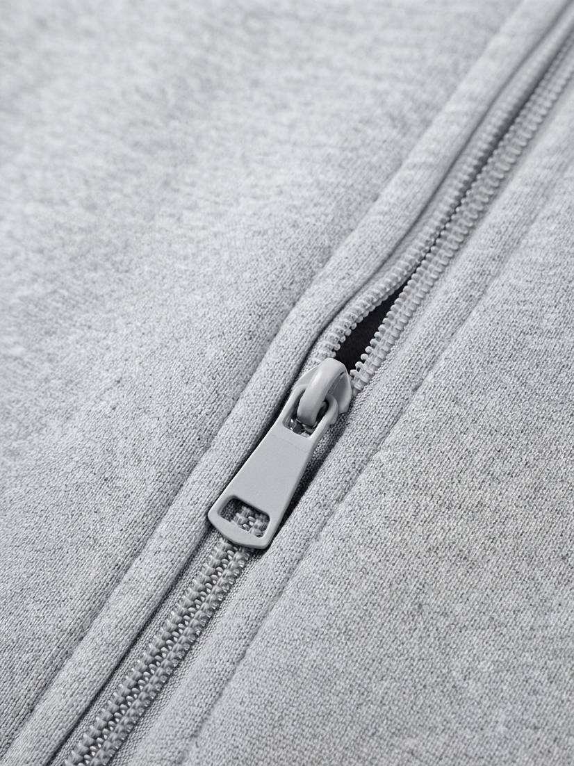 Close-up of a light gray heather fabric zipper with a matching gray pull tab.