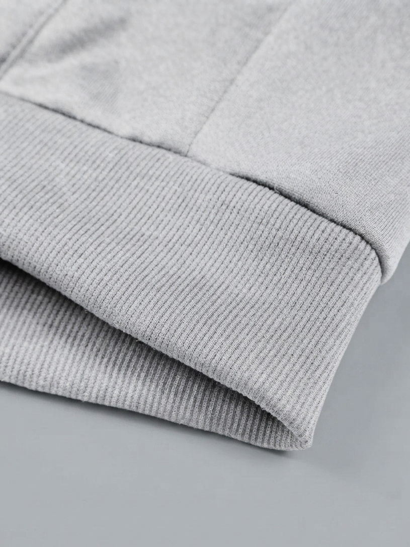 Close-up detail of a light gray ribbed knit fabric cuff, showing the texture and folded construction of a garment.