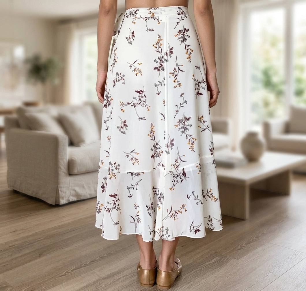 A woman wearing a white tiered midi skirt with a brown and beige floral print, standing in a bright, modern living room.