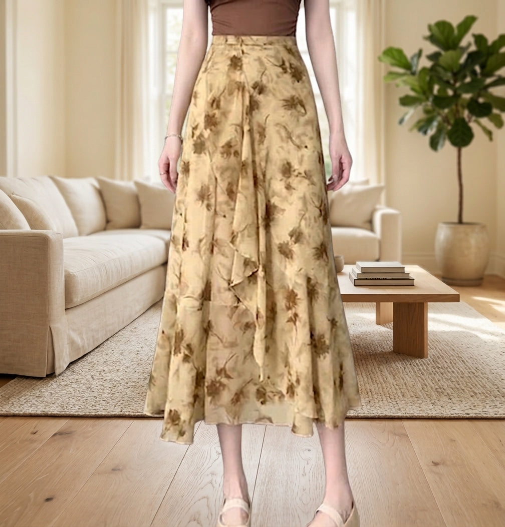 A woman wearing a high-waisted, midi-length A-line skirt with a brown and beige floral pattern, standing in a bright, modern living room with a beige sofa and wooden floor.